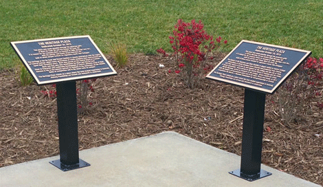 Two bronze plaques mounted on display stakes outdoors