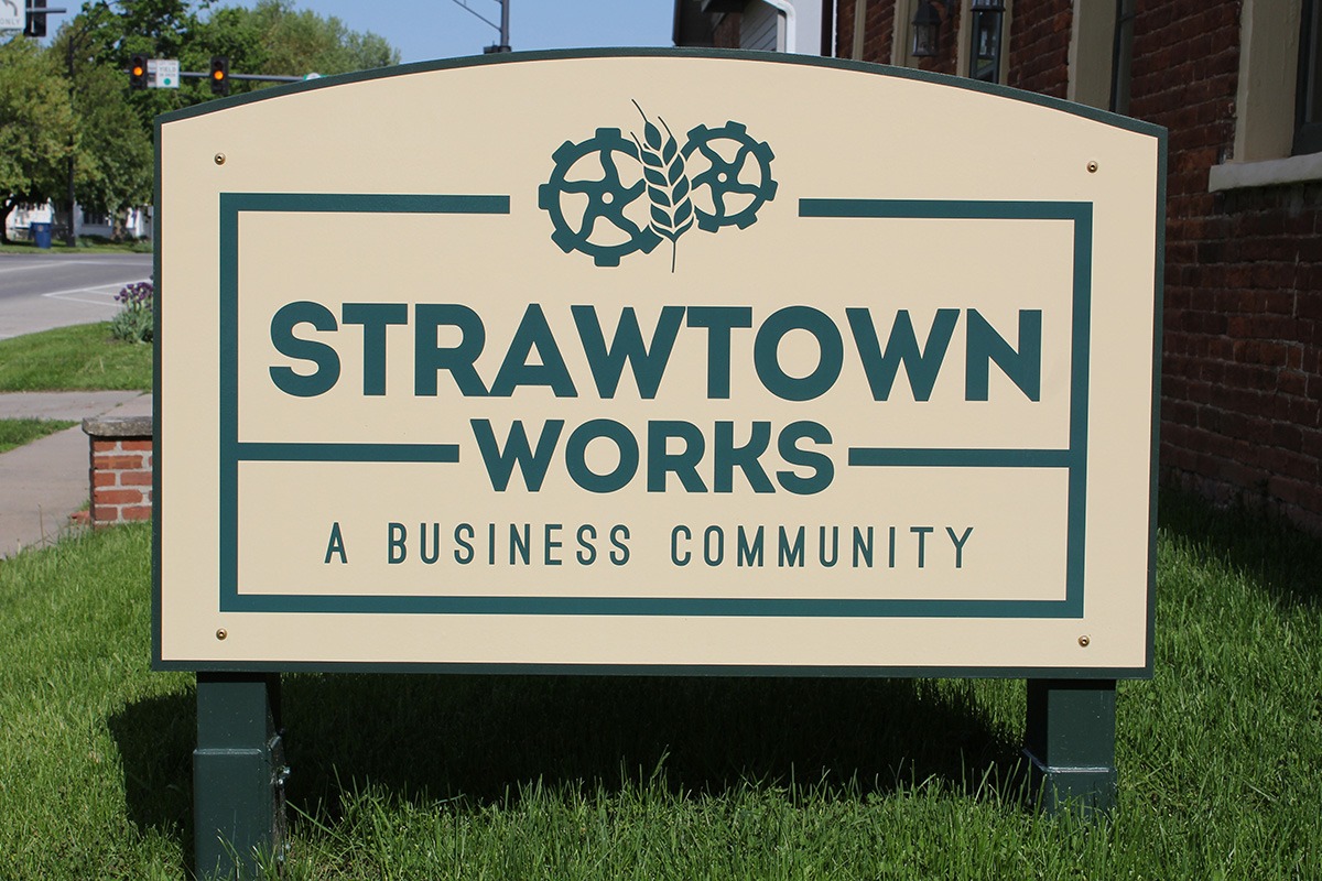 Tan and green freestanding storefront sign for Strawtown Works