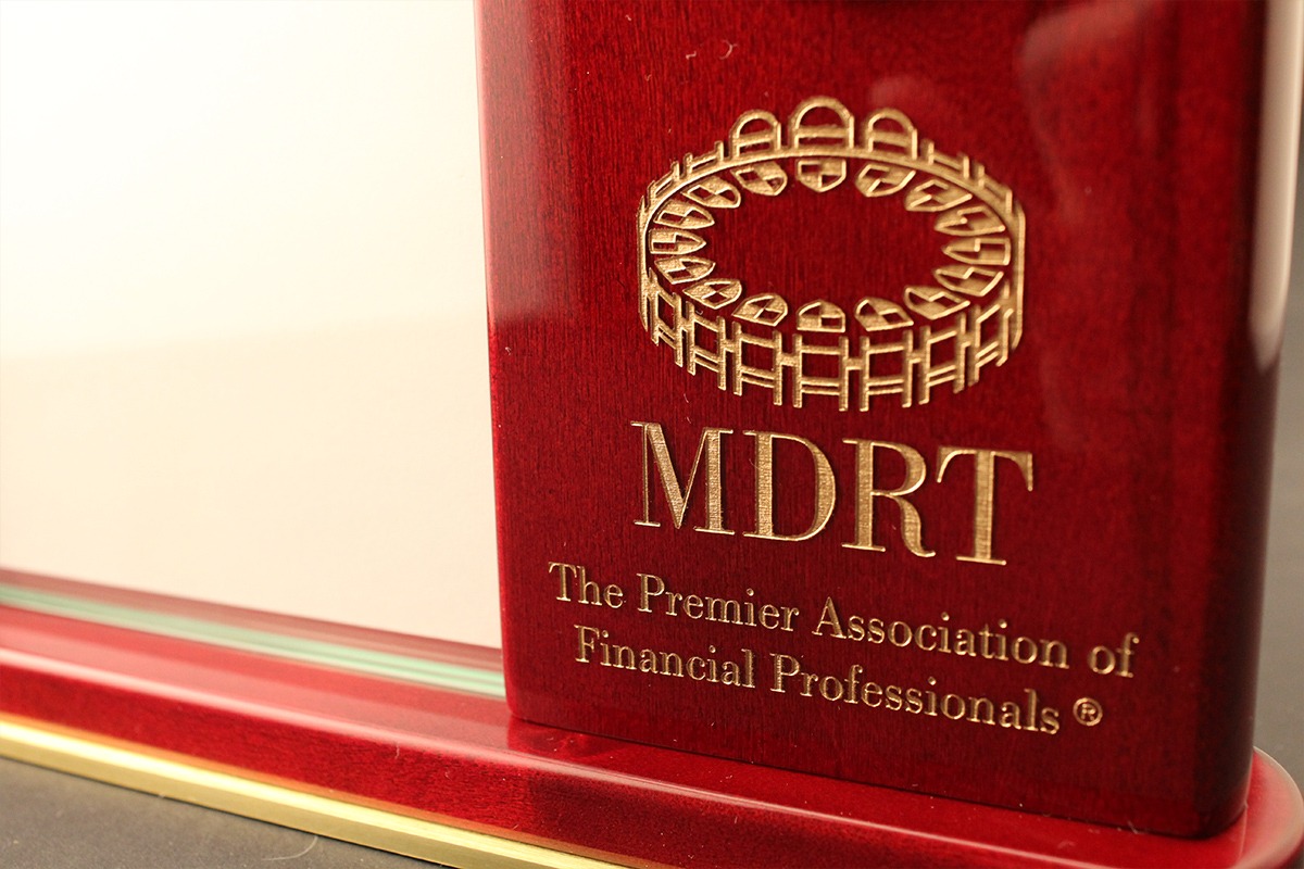 Closeup of gold MDRT logo laser-engraved on wooden clock