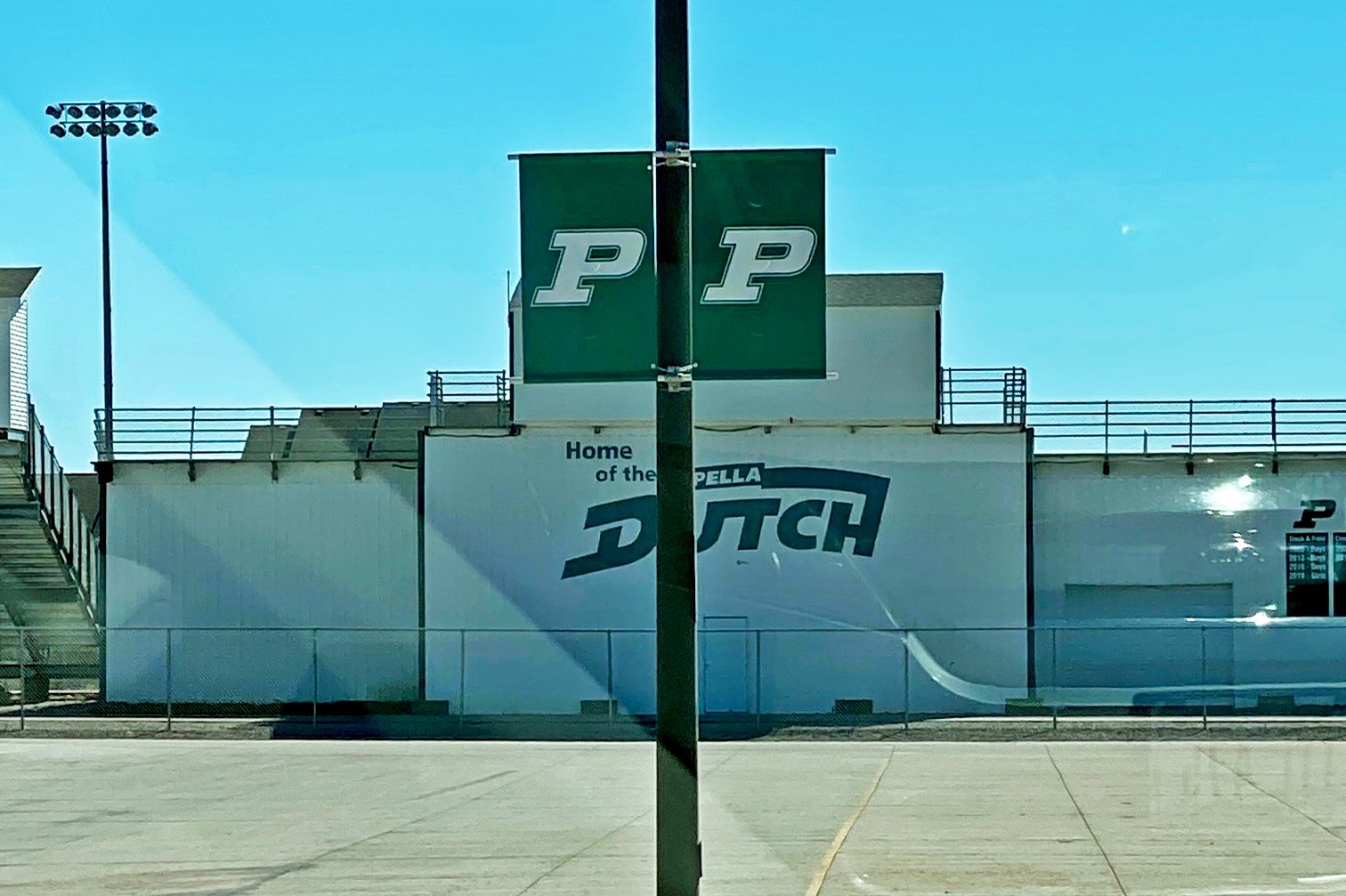 Two green banners with letter P on lampposts in front of school stadium