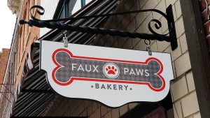 Faux Paws Bakery wall-mounted hanging storefront sign featuring bone and pawprint
